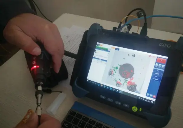Fiber end-face inspection probe is connected to a display showing a magnified connector end-face view.