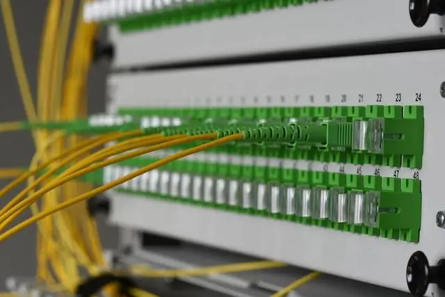 Yellow fiber patch cords connected to green adapters on a numbered fiber panel in the OTN network evolution section.