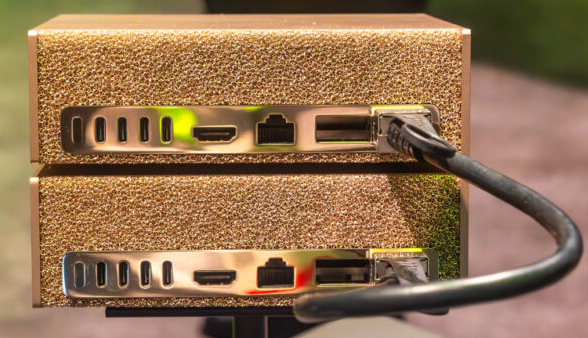 Two stacked NVIDIA DGX Spark systems with a black cable plugged into the rear ports for a direct device-to-device connection.